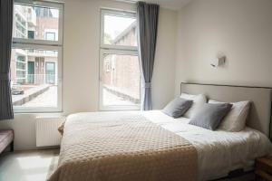 a bedroom with a large bed and two windows at Hotel Koemarkt in Purmerend