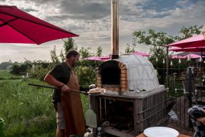 a man is cooking food in an outdoor oven at Luxe 4 pers chalet op minicamping in waarde in Waarde