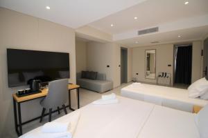 a hotel room with two beds and a desk and a tv at Niklas Boutique Hotel in Sarandë