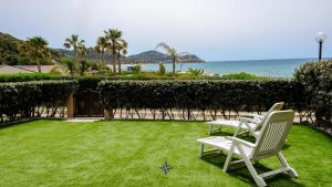a lawn with chairs and the ocean in the background at Villa Giulia seafront in Marongiu