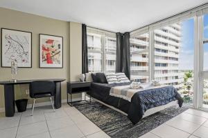 ein Schlafzimmer mit einem Bett, einem Schreibtisch und Fenstern in der Unterkunft Relaxing Escape Oceanfront Pool Gem On The Beach in Fort Lauderdale