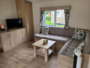 un soggiorno con un divano e un tavolo di Chalet bij Lente van Drenthe nabij meer a Gasselte