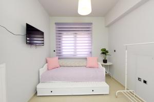 a white bedroom with a bed with pink pillows at Theros Lux Apartment in Émbonas