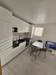 a kitchen with white cabinets and a table and chairs at Filip residence in Cluj-Napoca +8 photos