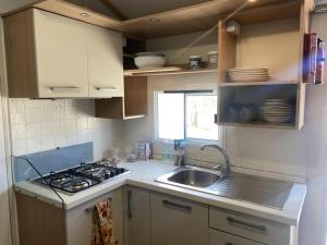 a small kitchen with a stove and a sink at Baia del Principe MobilHome in Oliveri