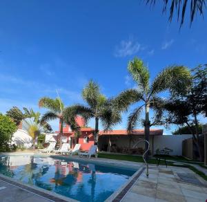 a swimming pool with palm trees next to a house at Jardim das Dunas in Canoa Quebrada