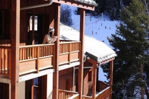 a woman standing on the balcony of a ski lodge at Résidence Goélia Les Balcons d'Anaïs in La Norma