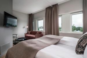 a hotel room with a bed and a chair and windows at Quality Hotel Edvard Grieg in Bergen +45 photos