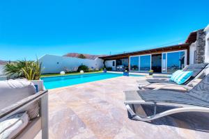 a patio with two lounge chairs and a swimming pool at Villa Macher Piscina y Bar piscina in Tías