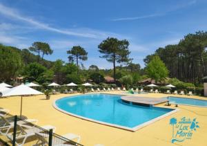 ein Pool in einem Resort mit Liegestühlen und Sonnenschirmen in der Unterkunft Village Vacances Le Lac Marin in Soustons