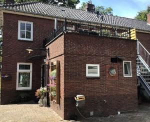 a red brick house with a balcony on top of it at Om De Hoek in Norg
