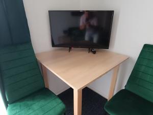 a tv sitting on a desk with two green chairs at Green Rooms Gdańsk in Gdańsk