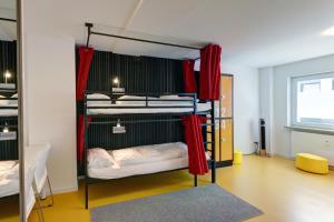 曼海姆Hostel Mannheim的客房设有两张双层床和红色窗帘