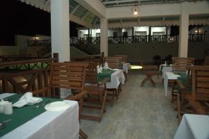 a restaurant with wooden tables and chairs with green tablecloths at Alfa Boutique Hotel in Kiwengwa