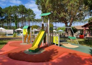 ein Spielplatz mit Rutsche in einem Park in der Unterkunft Village Vacances Le Lac Marin in Soustons