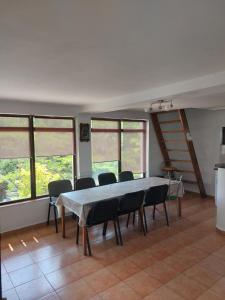 a table and chairs in a room with windows at Casa de Vacanta Simfonia Apelor in Dunavăţu de Jos