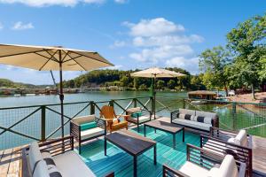 eine Terrasse mit Stühlen und Tischen und einem Gewässer in der Unterkunft Little Lake Cottage in Lake Lure