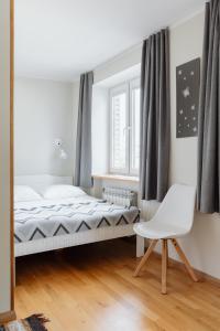a bedroom with a bed and a white chair at Sweet Home apartment in Haapsalu