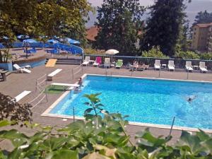a large blue swimming pool with people sitting around it at Selva Coccinella in Cissano