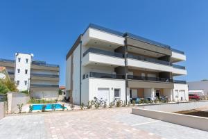 an apartment building with a swimming pool in front of it at Sea&Sand Apartment - Modern Sea View near Sandy Beaches in Privlaka