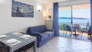 a living room with a blue couch and a table and a balcony at Selva Coccinella in Cissano +9 photos