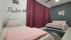 a bedroom with two beds with pink sheets at ZDQ Homestay in Kampong Padang Keladi