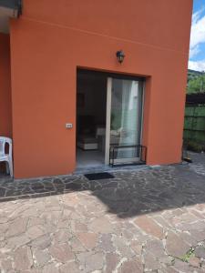 an orange building with a sliding glass door at La Rosa di Emma in Porlezza
