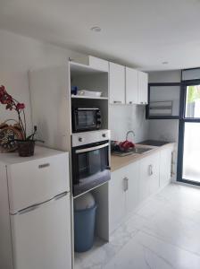 a white kitchen with white cabinets and appliances at Appartement moderne proche Paris, aéroport et disneyland in Le Perreux-Sur-Marne