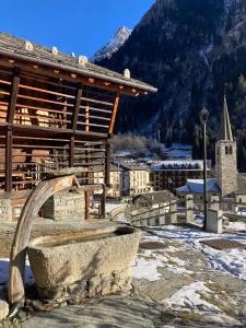 a stone bench in front of a building with a church at Stilish wooden chalet fully renovated near the lifts in Alagna Valsesia