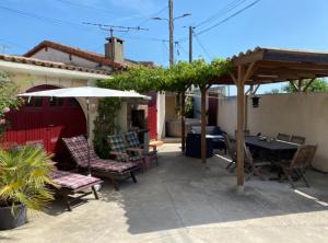 a patio with a table and chairs and an umbrella at APPARTEMENT TOUT CONFORT AVEC PARKING FERMÉ in Arles