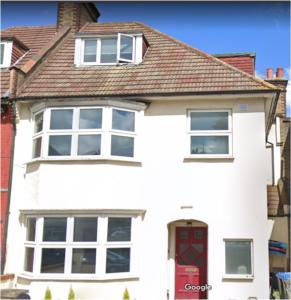 a white house with a red door and windows at Amazing 6 bedroom house with free parking on site. in Norbury