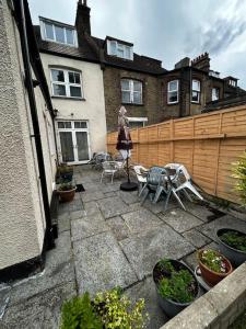 a woman walking on a patio in front of a house at Amazing 6 bedroom house with free parking on site. in Norbury