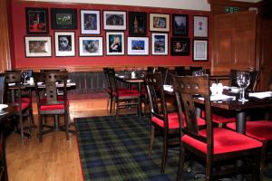 ein Restaurant mit Tischen und Stühlen und Bildern an der Wand in der Unterkunft Ashtree House Hotel, Glasgow Airport & Paisley in Paisley