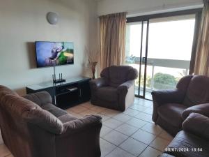 a living room with two couches and a flat screen tv at Stella Maris 55 in Amanzimtoti