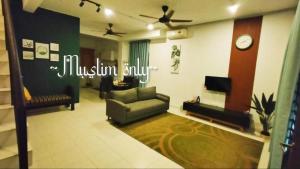 a living room with a couch and a clock on the wall at ZDQ Homestay in Kampong Padang Keladi