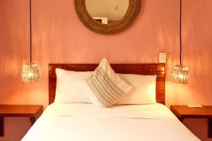 a bedroom with a bed with white sheets and a mirror at Casa Losodeli & Coworking- Adults Only in Puerto Escondido