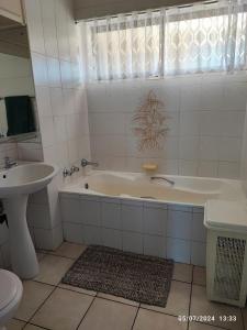 a white bathroom with a tub and a sink at Stella Maris 55 in Amanzimtoti