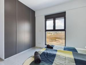 a bedroom with a bed with a large window at Modern Apart only Steps from Beach in Larnaka