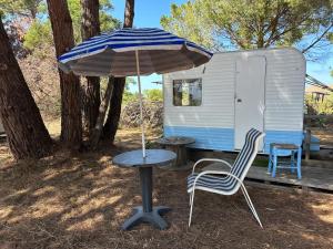 a table and two chairs and an umbrella next to a trailer at Caravane amy on the beach in Lucciana