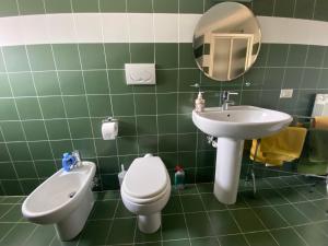 a green tiled bathroom with a toilet and a sink at Da Vittoria in Albissola Marina