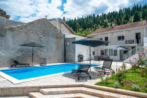 a swimming pool with two chairs and umbrellas next to a house at Vila Hana in Stolac