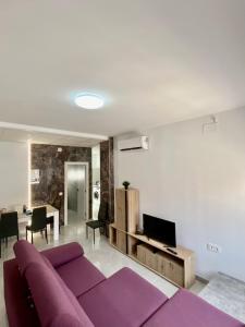 Una sala de estar con un sofá morado y un televisor. en Paradise Costa en Los alcázares, en Los Alcázares