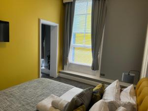 a bedroom with a bed with yellow walls and a window at The Red Lion Hotel in Cromer