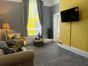 a living room with a couch and a tv on a wall at The Red Lion Hotel in Cromer