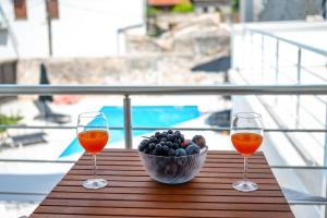two glasses of wine and a bowl of fruit on a table at Vila Hana in Stolac
