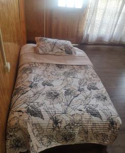un lit dans une chambre avec une couette et des oreillers dans l'établissement Cabaña muy confortable con buena ubicación y acceso, à Puerto Montt