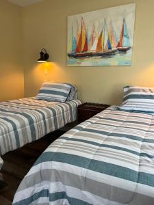 two beds in a room with sailboats on the wall at MacGregors But and Ben in Pictou