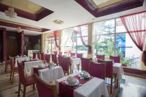 a restaurant with white tables and chairs and windows at Hotel Residence Rihab in Agadir