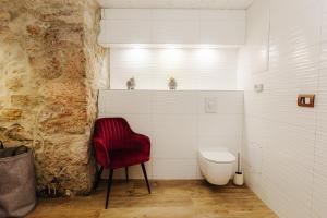 a bathroom with a red chair and a toilet at GOZDNE VILE va VRTI in Kostel