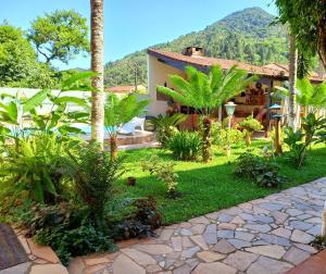 a house with a garden in front of a mountain at Chalé da Ju in Ubatuba